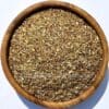 Houten kom met losse groene rooibos bio thee zonder cafeïne, ideaal voor een gezonde theepauze.