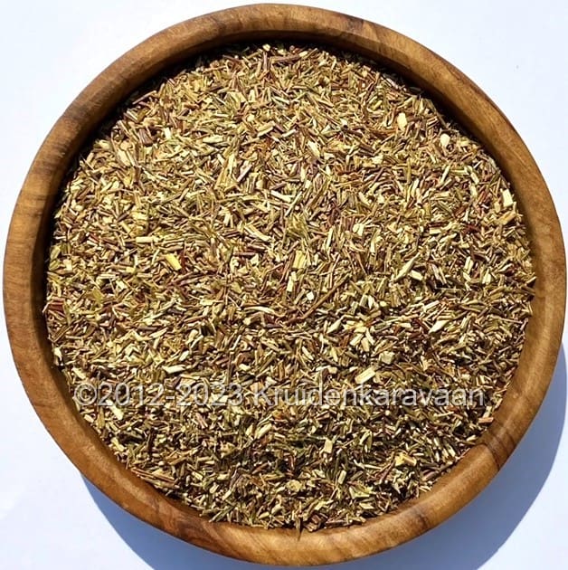 Houten kom met losse groene rooibos bio thee zonder cafeïne, ideaal voor een gezonde theepauze.